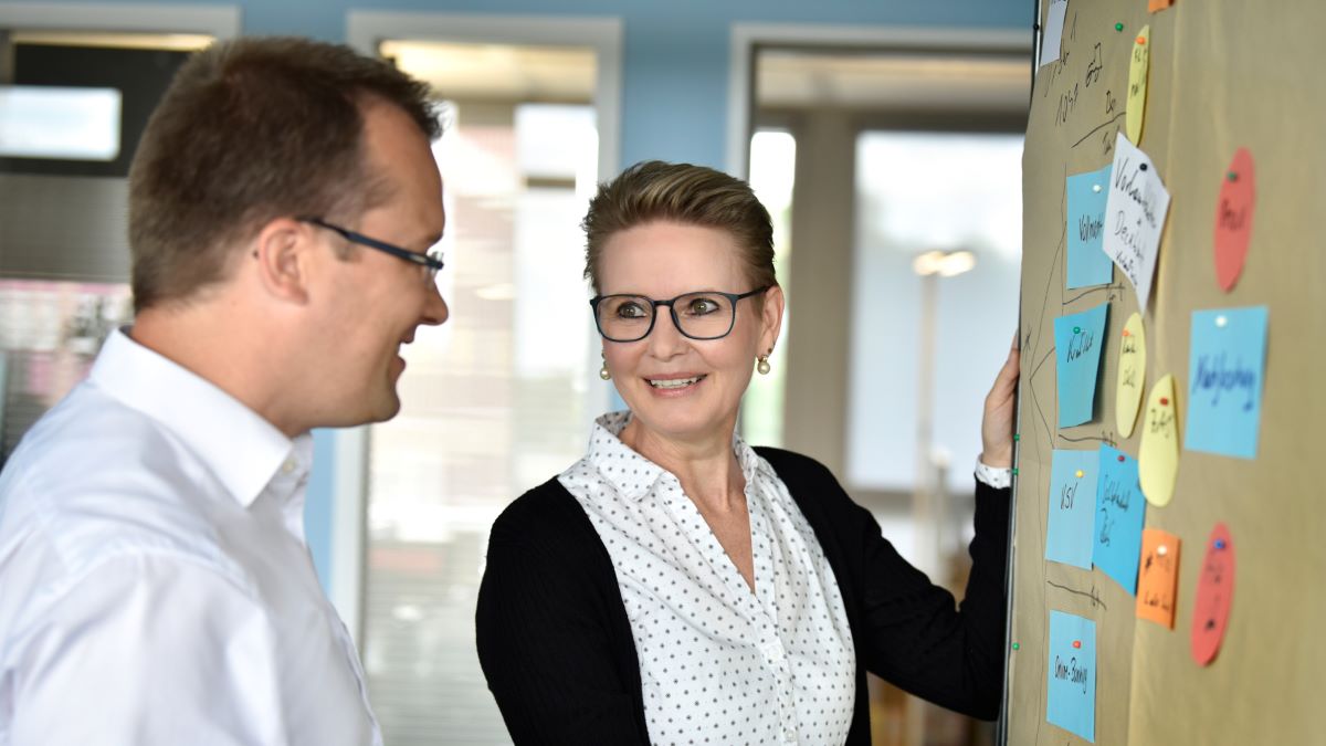 Zwei Mitarbeitende der apoData stehen an einer Pinnwand